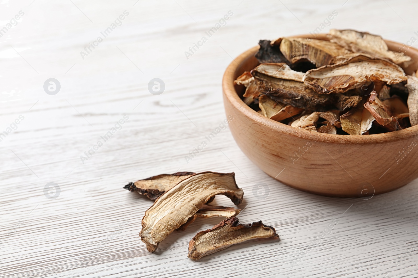 Photo of Bowl of dried mushrooms on wooden background. Space for text