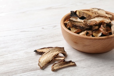 Bowl of dried mushrooms on wooden background. Space for text