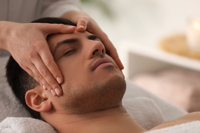 Photo of Man receiving facial massage in beauty salon, closeup