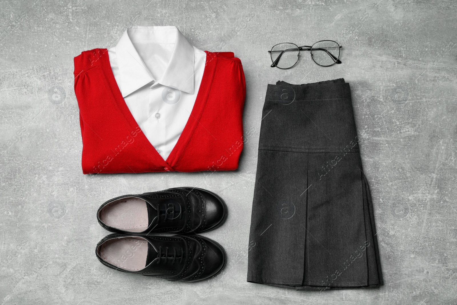 Photo of Stylish school uniform for girl and glasses on grey background, flat lay