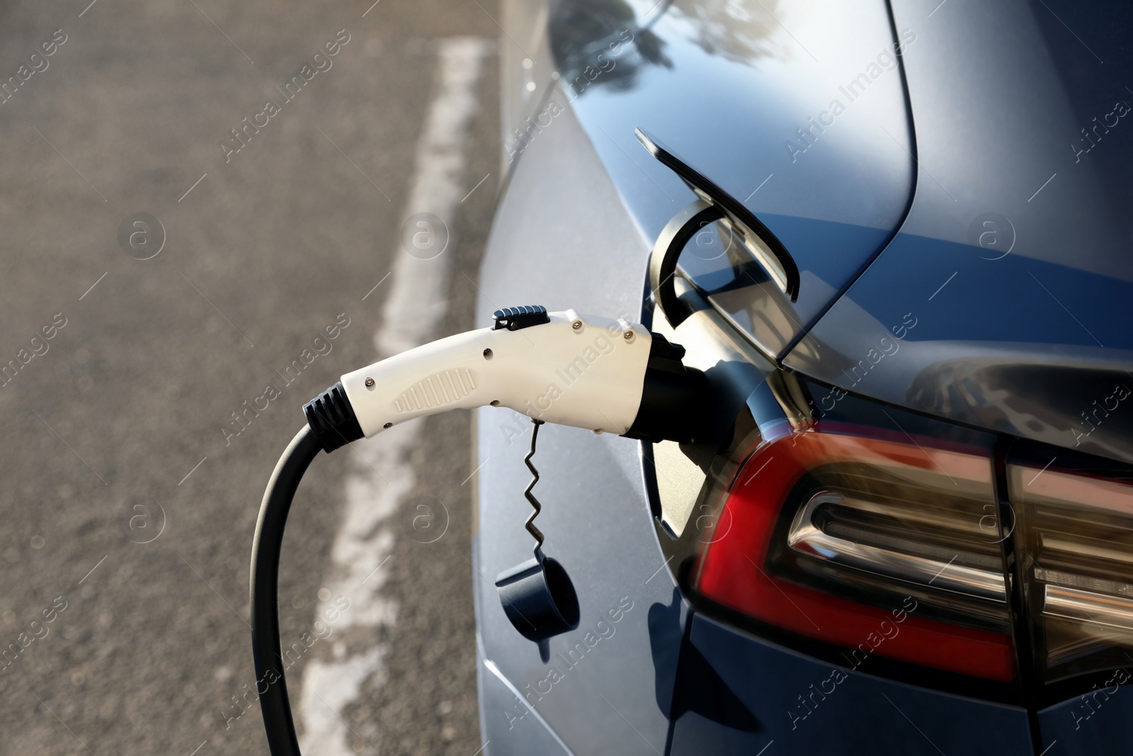 Photo of Charging modern electric car from station outdoors, closeup