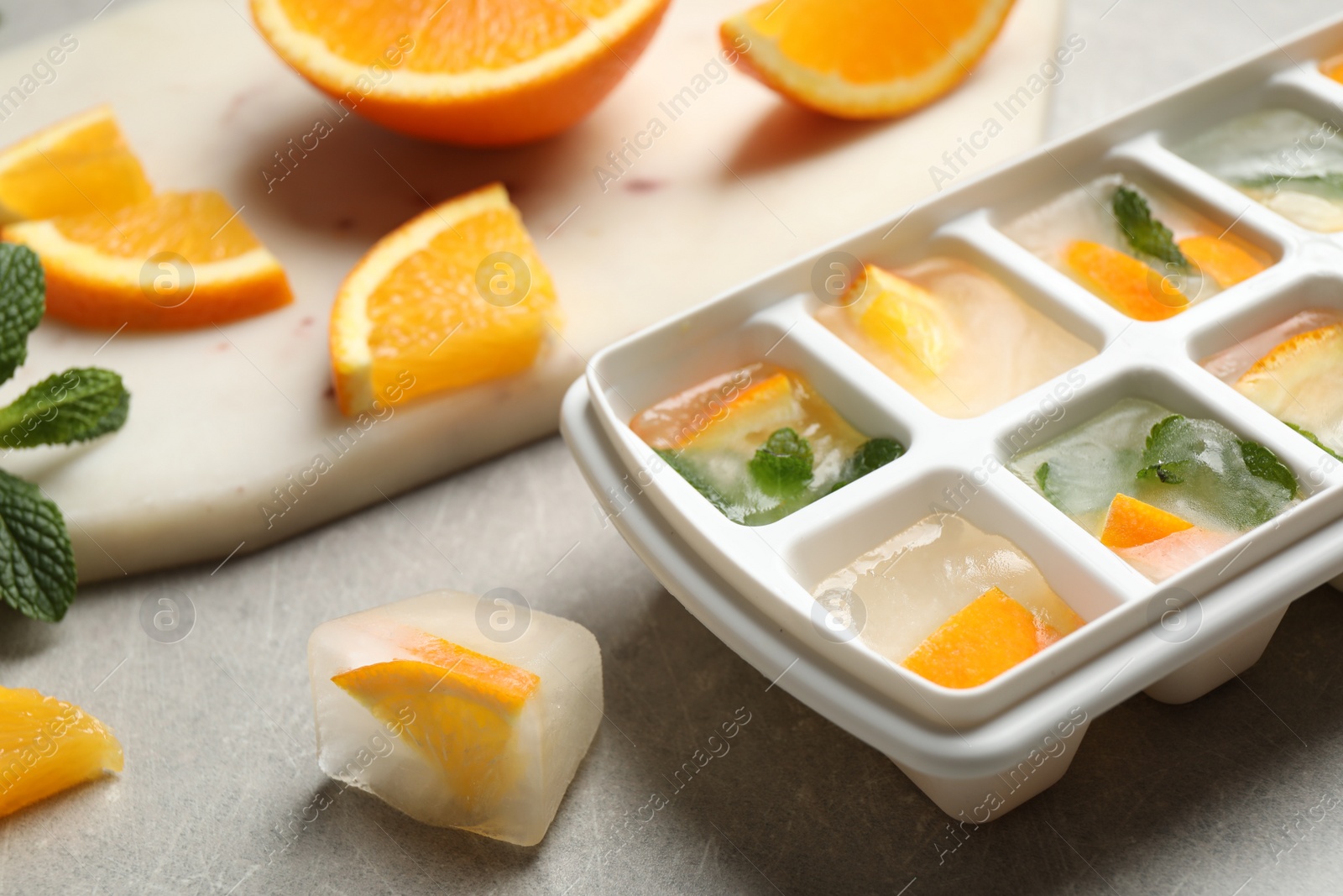 Photo of Ice cubes with orange and mint on light table, closeup