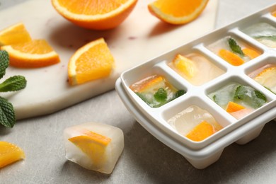 Ice cubes with orange and mint on light table, closeup