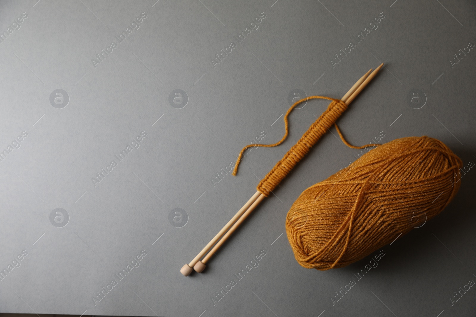 Photo of Soft orange yarn, knitting and needles on light grey background, top view. Space for text