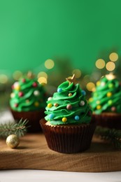 Tasty Christmas cupcakes on wooden board, closeup