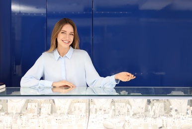 Photo of Portrait of young saleswoman near showcase in jewelry store