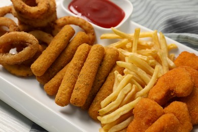 Photo of Tasty ketchup and different snacks on table, closeup