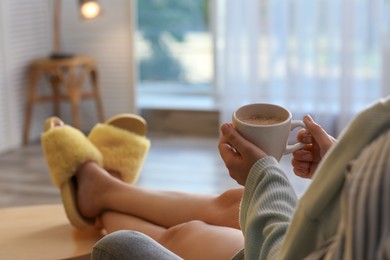 Woman with cup of aromatic coffee relaxing at home, closeup. Space for text