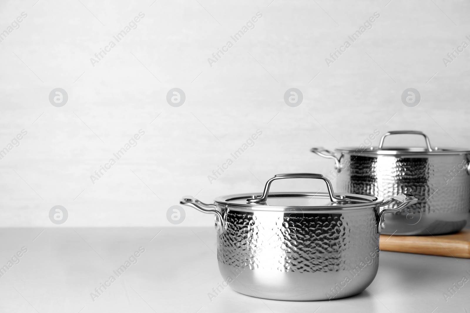 Photo of Clean saucepans on table against light background. Space for text