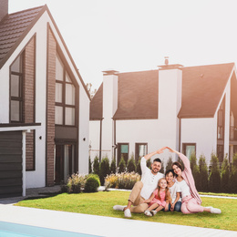 Image of Happy family sitting and smiling near their new house