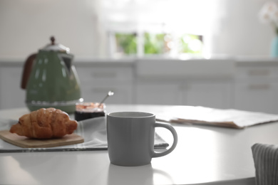 Delicious breakfast with fresh croissant and cup of hot drink in kitchen