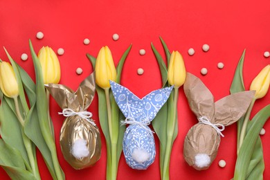 Photo of Flat lay composition with Easter bunnies made of paper and eggs on red background