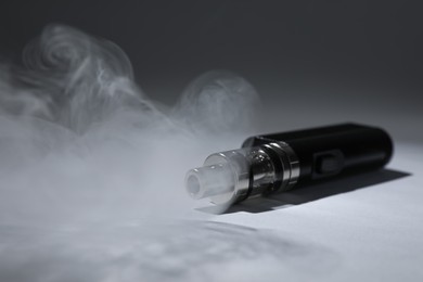 Photo of Electronic cigarette and smoke on grey background, space for text