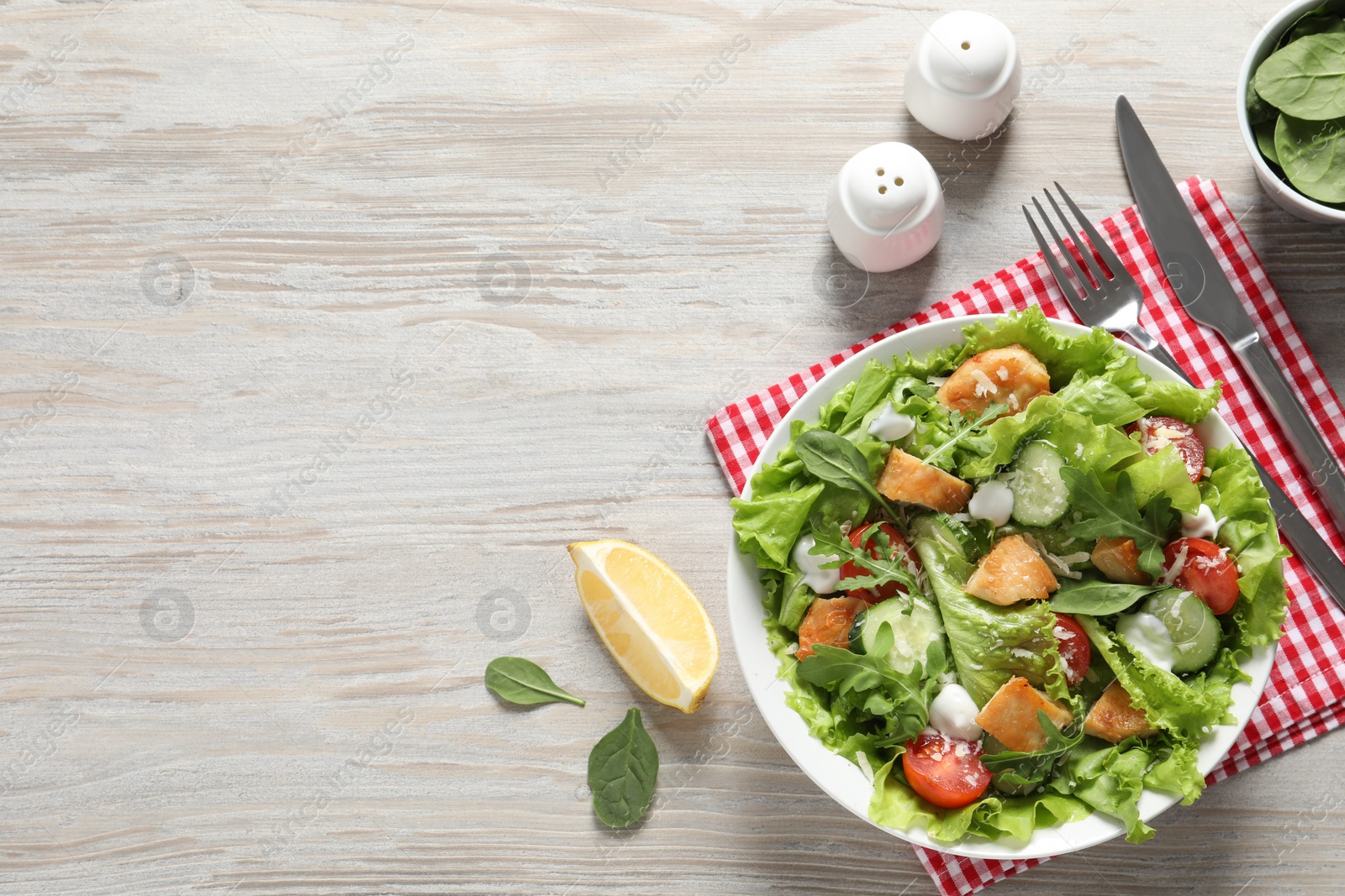 Photo of Delicious salad with chicken and vegetables served on wooden table, flat lay. Space for text