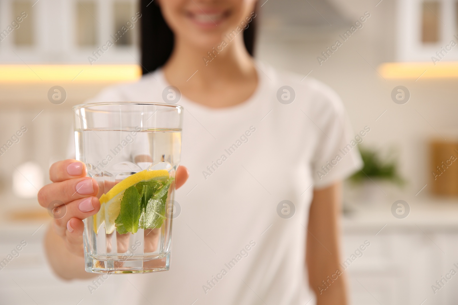 Photo of Young woman with glass of fresh lemonade at home, closeup