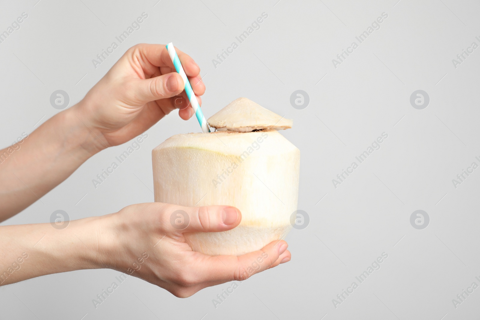 Photo of Woman with fresh coconut drink in nut on light background, closeup