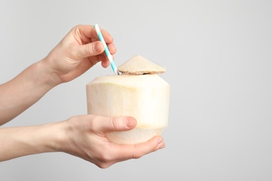 Photo of Woman with fresh coconut drink in nut on light background, closeup