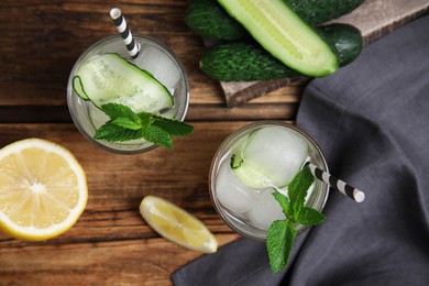 Tasty fresh cucumber water and ingredients on wooden table, flat lay