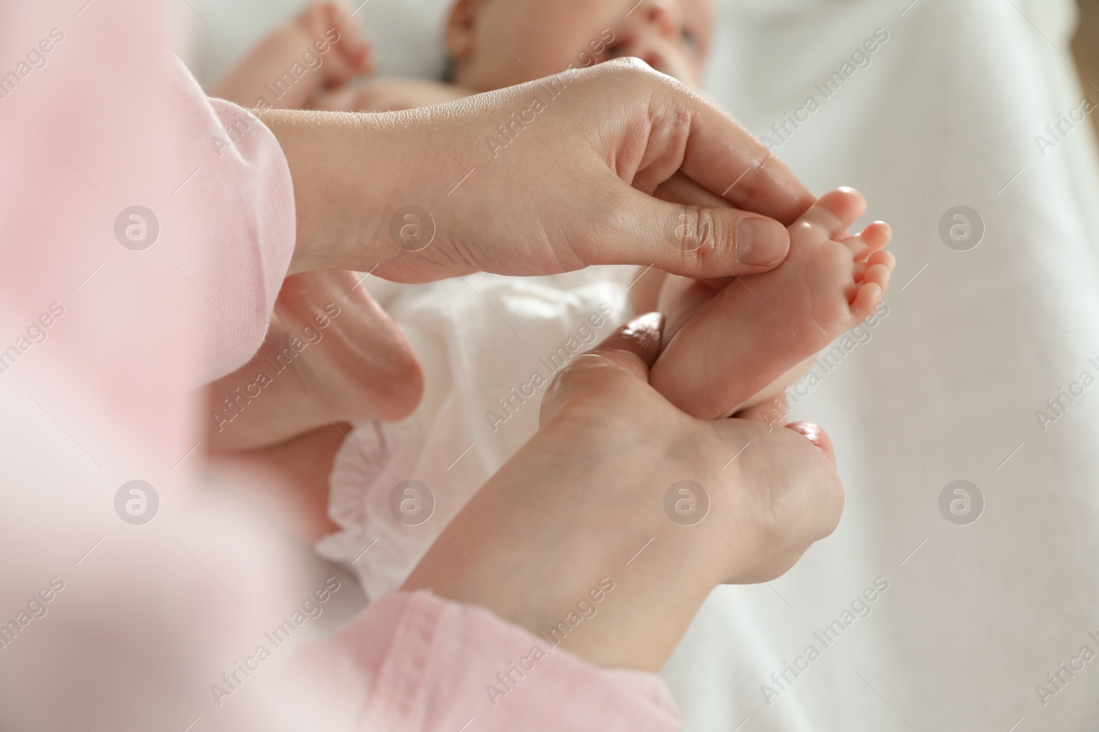 Photo of Mother massaging her cute baby with oil, closeup