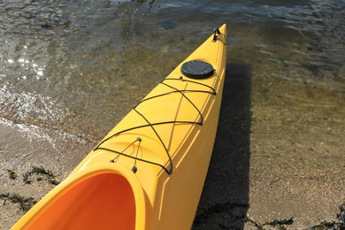 Photo of Yellow kayak on beach near river, closeup. Summer camp activity