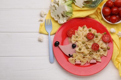 Creative serving for kids. Plate with cute hedgehog made of delicious pasta, sausages and tomatoes on white wooden table, flat lay. Space for text