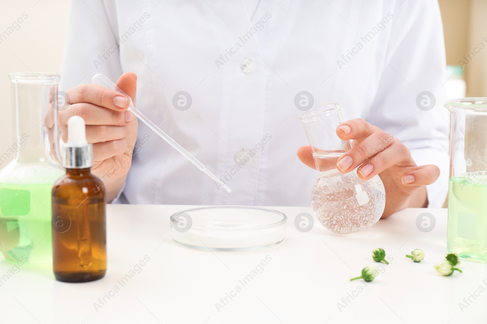 Photo of Female dermatologist creating skin care product at table, closeup