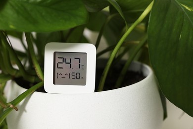 Digital hygrometer with thermometer on flower pot, closeup. Space for text