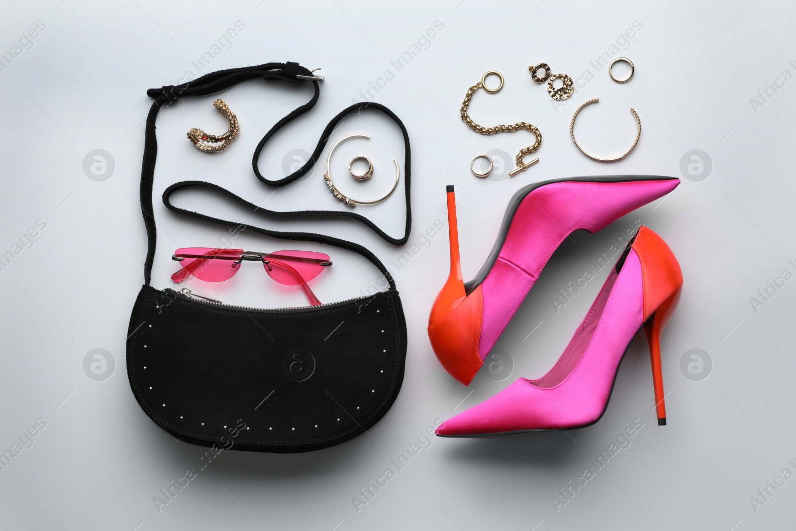 Photo of Stylish woman's bag, shoes, sunglasses and bijouterie on light background, flat lay