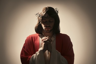 Photo of Jesus Christ with crown of thorns praying on light background