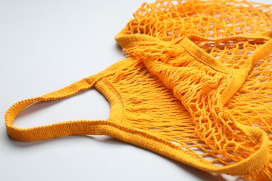Photo of Orange string bag on light grey background, closeup
