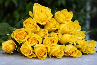 Beautiful bouquet of yellow roses on light table outdoors, closeup