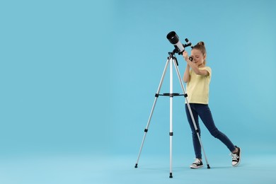 Little girl looking at stars through telescope on light blue background, space for text