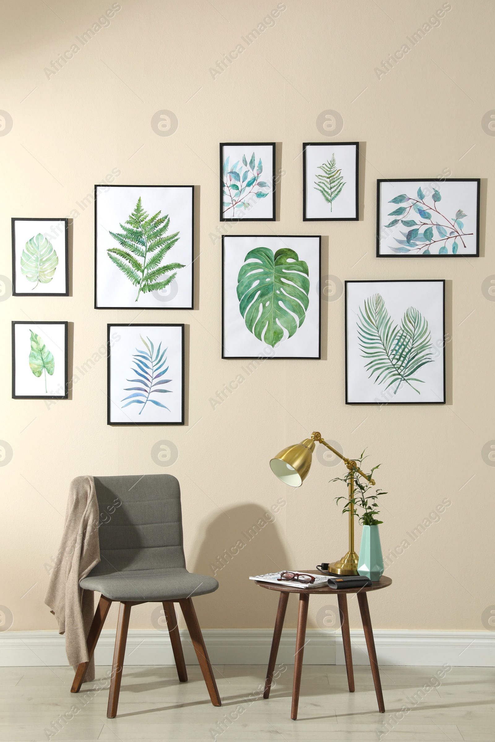 Photo of Beautiful paintings of tropical leaves on beige wall in room interior