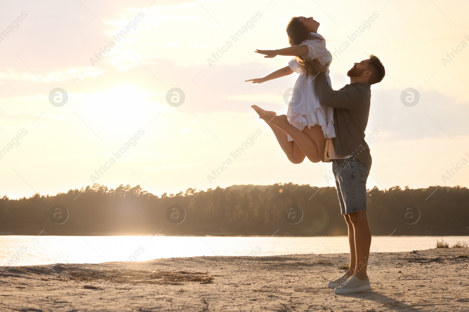 Photo of Happy couple dancing near river at sunset. Space for text