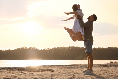 Photo of Happy couple dancing near river at sunset. Space for text