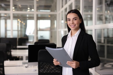 Happy woman with folder in office, space for text. Lawyer, businesswoman, accountant or manager