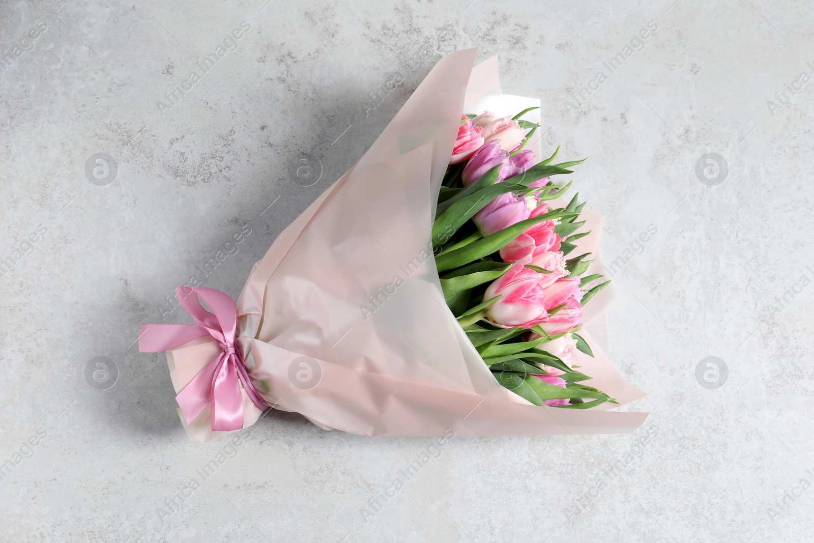 Photo of Bouquet of beautiful tulips on white table, top view