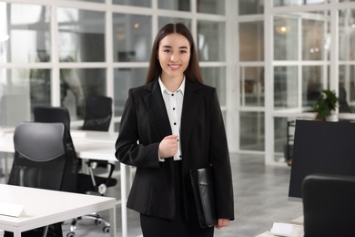 Photo of Happy real estate agent with leather portfolio in office