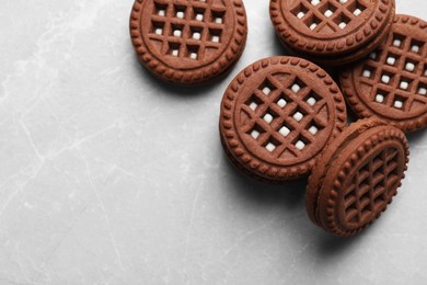 Tasty chocolate sandwich cookies with cream on light grey marble table, flat lay. Space for text