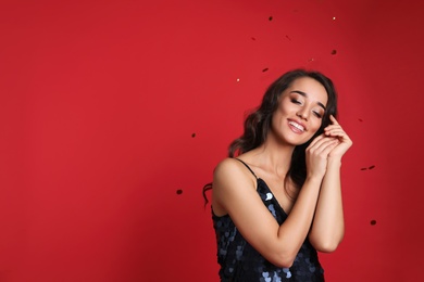 Photo of Beautiful young woman wearing elegant dress on red background, space for text. Christmas party