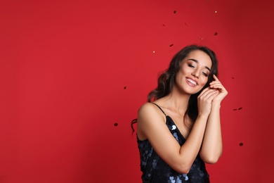 Beautiful young woman wearing elegant dress on red background, space for text. Christmas party