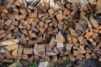 Photo of Stack of cut firewood on green grass outdoors