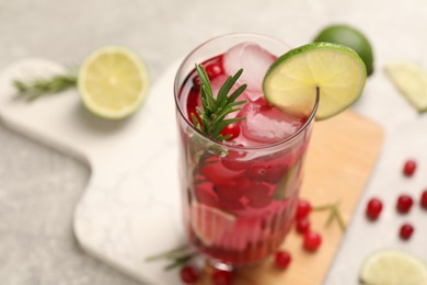 Tasty cranberry cocktail with rosemary and lime in glass on table, closeup. Space for text