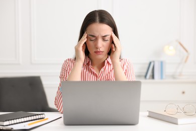 Young woman suffering from headache at workplace in office