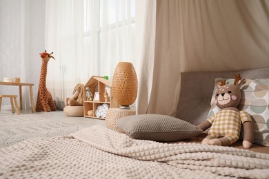Cozy kids room with play tent, toys and comfortable floor bed. Montessori interior