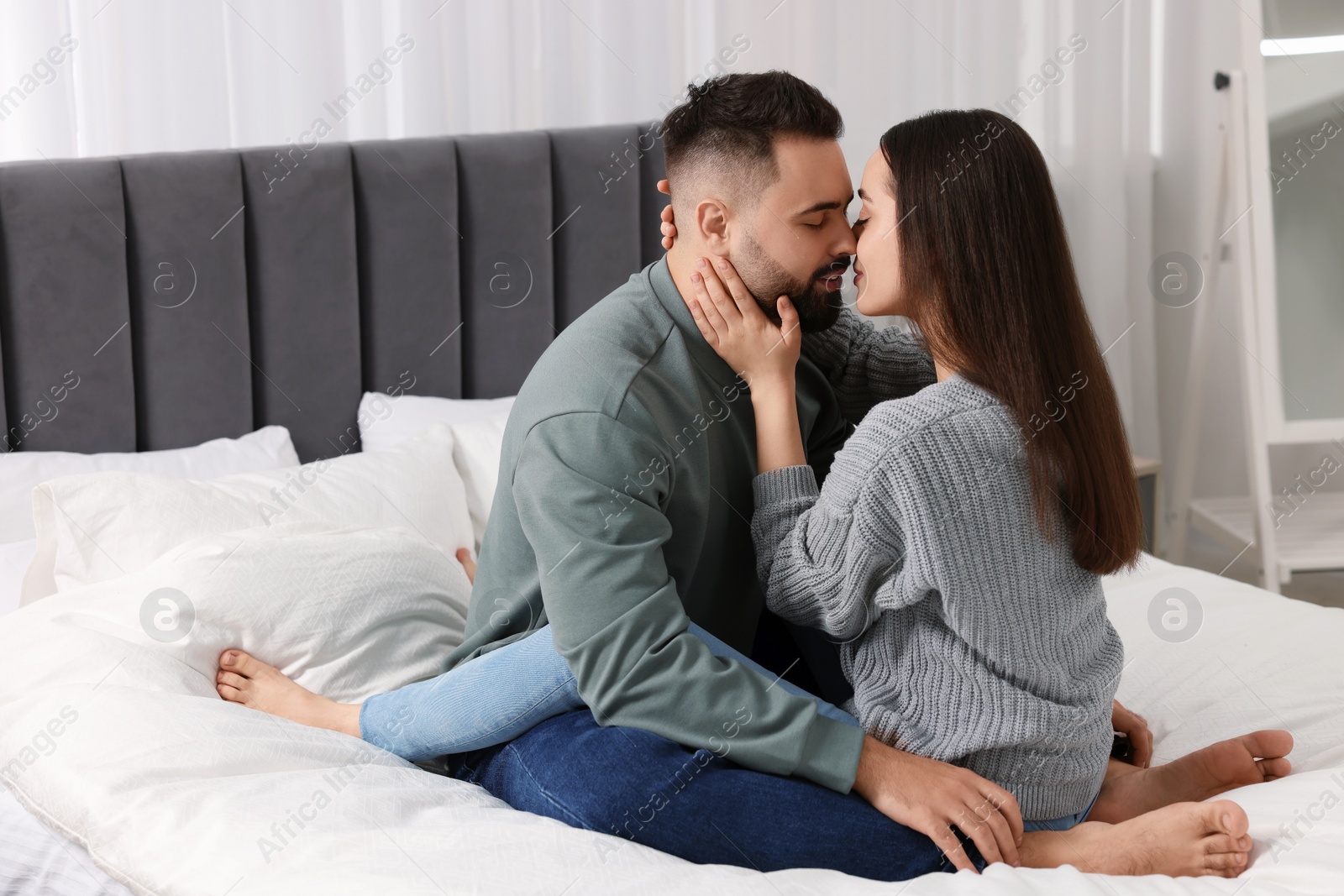 Photo of Affectionate young couple kissing in bedroom. Space for text