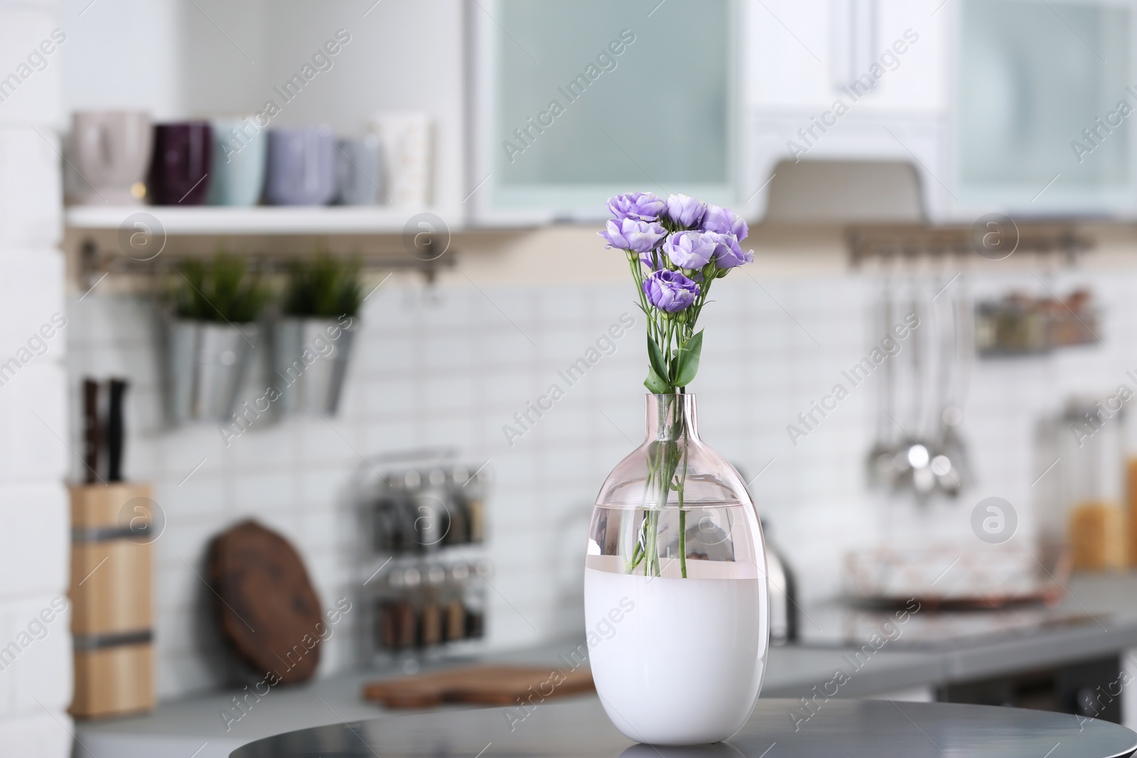 Photo of Vase with beautiful flowers on table in kitchen interior