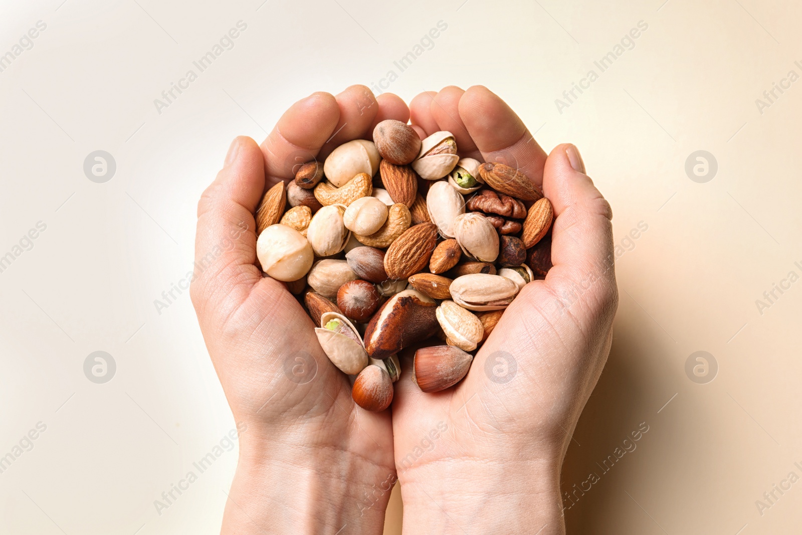 Photo of Woman holding organic mixed nuts on color background, closeup