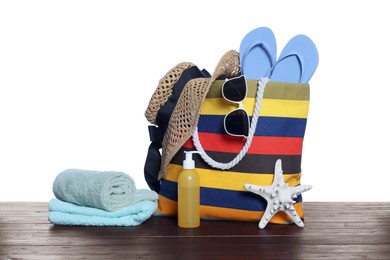 Photo of Stylish bag, starfish and other beach accessories on wooden table against white background