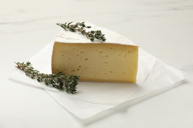 Photo of Piece of tasty camembert cheese and thyme on white table, closeup
